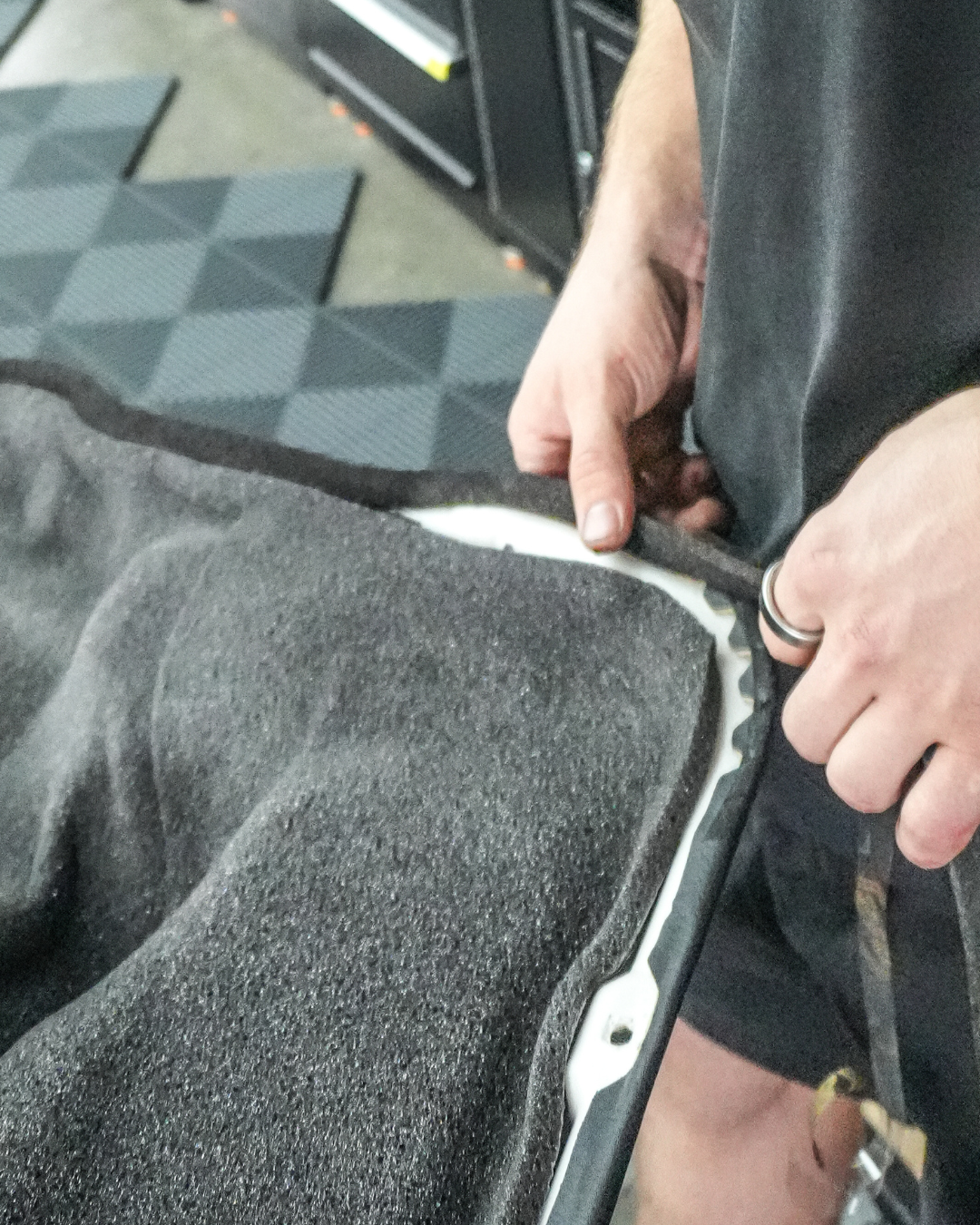 Person fitting automotive soundproofing material using StP Bitoplast Anti Noise Tape on vehicle door panel edge for car noise reduction and vibration damping.