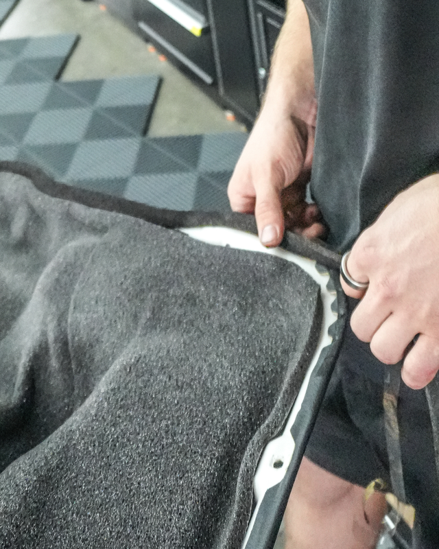 Person fitting automotive soundproofing material using StP Bitoplast Anti Noise Tape on vehicle door panel edge for car noise reduction and vibration damping.