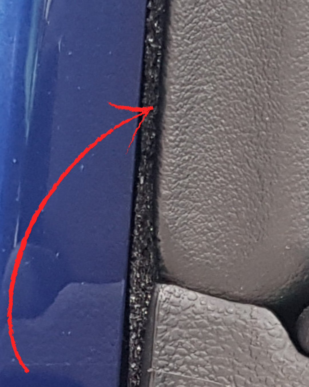 Close-up view of dark textured StP Bitoplast Anti Noise Tape installed between a blue painted car surface and black interior trim to provide sound and vibration damping.