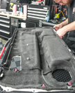 A technician installs Sound Absortion StP Biplast soundproofing material on an automotive interior panel, enhancing car noise reduction and vibration damping.